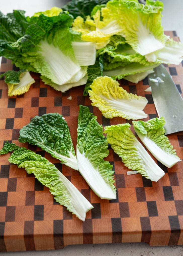Individual leaves of Bomdong cabbage cut into bite-size pieces on a wooden board