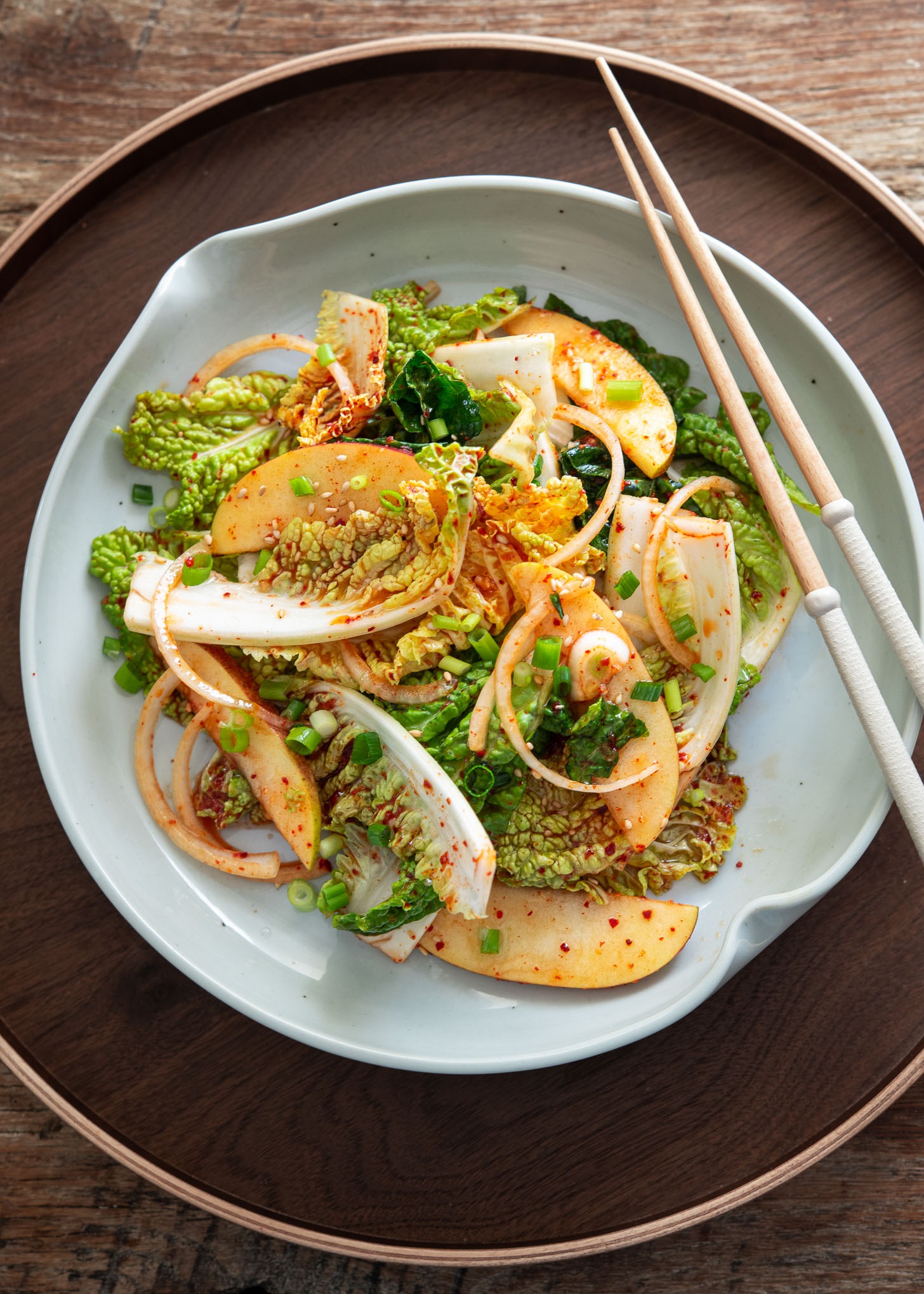 Top-down view of crunchy Korean spring cabbage salad (bomdong) in a grey bowl with chopsticks.