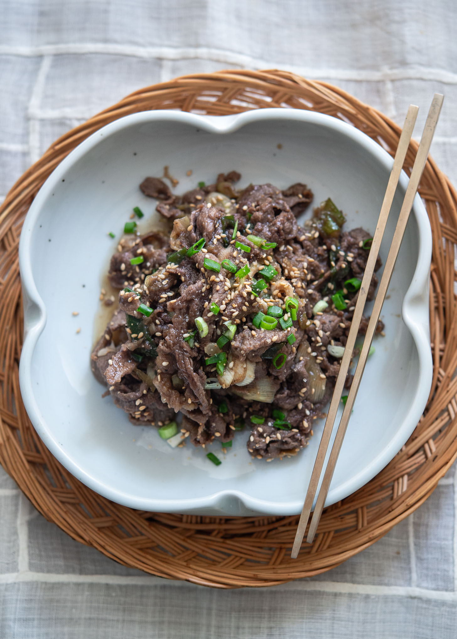 Authentic Korean beef bulgogi in a serving dish topped with chopsticks.