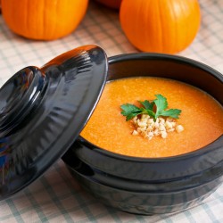 Korean pumpkin porridge is served in a stone pot surrounded by pumpkins