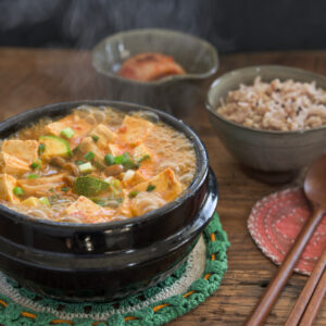 Hot boiling doenjang jjigae in a stone pot is a served with rice and kimchi