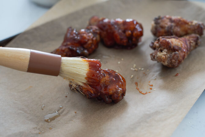 Fried chicken wings are brushed with gochujang sauce