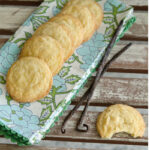 Vanilla bean sugar cookies on a napkin next to vanilla beans.