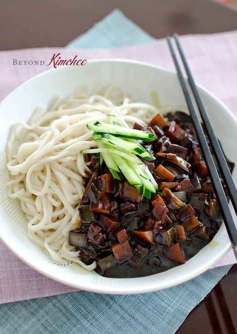 White wheat noodles are served with jjajangmyeon sauce and topped with cucumber slices.