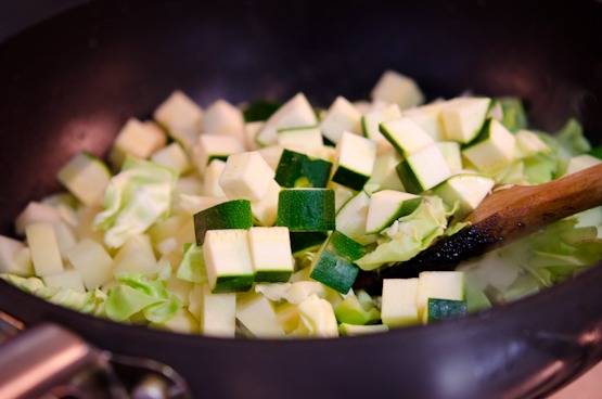 Vegetables are added to the pork in a wok.