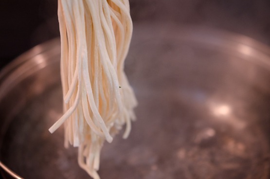 Wheat noodles are about to drop in a pot of boiling water.