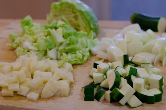 Cabbage, onion, potato, and zucchini are cut into small cubes.