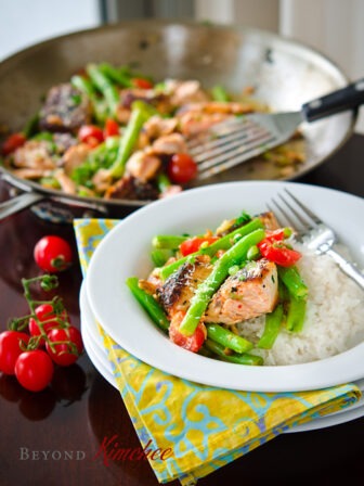 Salmon fillet with green beans and tomatoes cooked in a savory sauce and served with rice.