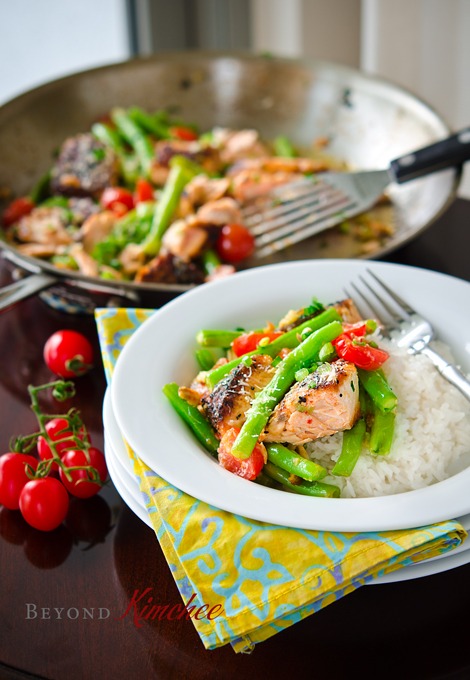 Salmon fillet with green beans and tomatoes cooked in a savory sauce and served with rice.