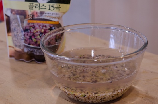 Various mixed grains soaking in water in a bowl.