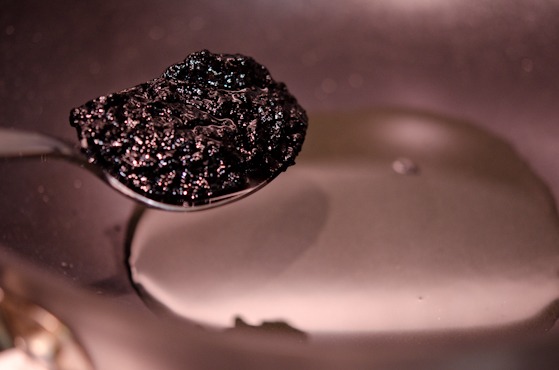 A spoonful of roasted black bean paste is draining off the excess oil.