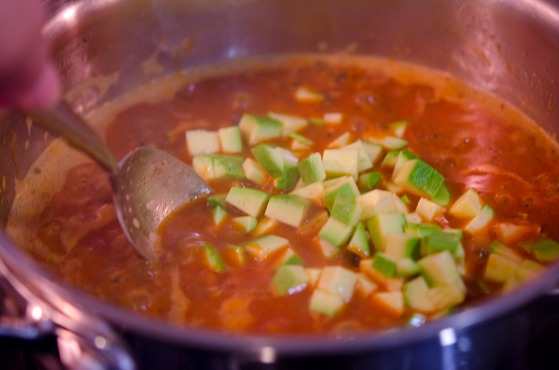 Zucchini pieces are added to the simmering topping sauce.