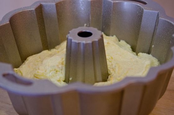 Orange cake batter is panned in a greased bundt pan.