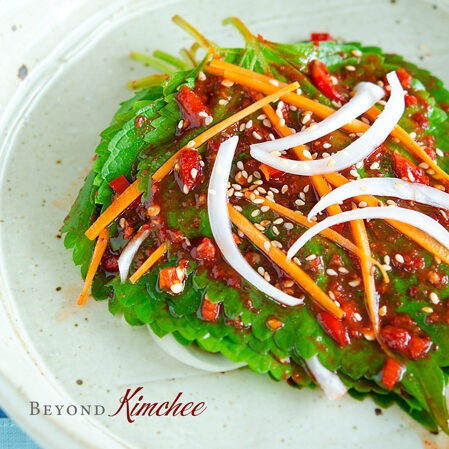 Perilla Kimchi is topped with spicy chili sauce with carrot and onion slices.