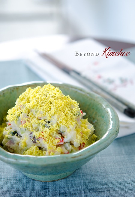 Korean Potato Salad is topped it egg yolk crumbs in a bowl.