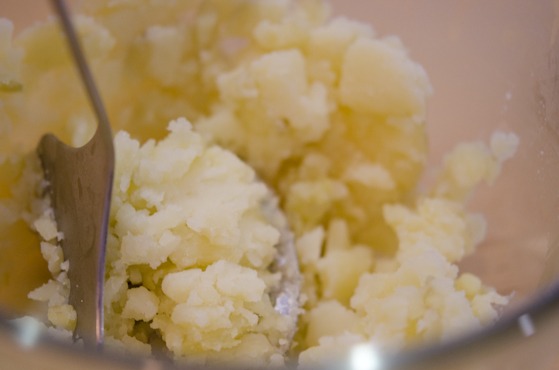 Cooked potatoes are being mashed.