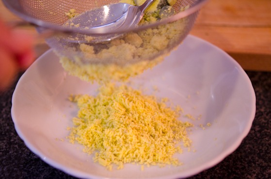 Egg yolks are pressed through strainer to get fine crumbs.