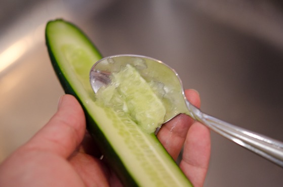 Seeds are removed from the cucumber using a spoon.