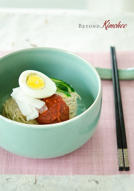 Naengmyeon, the Korean style spicy cold noodles, are topped with sauce and hard boiled egg