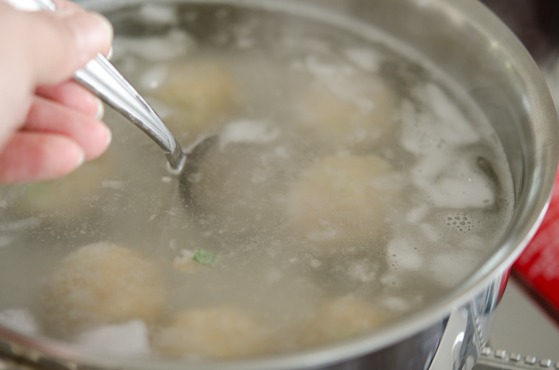 Dumpling balls are gently tossed in a simmering water.