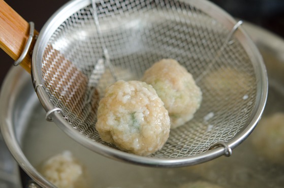 Nude dumpling balls are strained from the water.