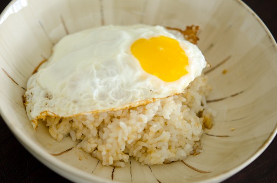 Sunny side up egg is topped over rice in a bowl.
