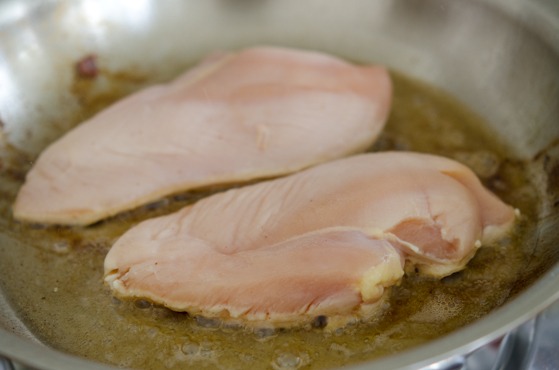 Chicken breast are cooking in a bacon grease.