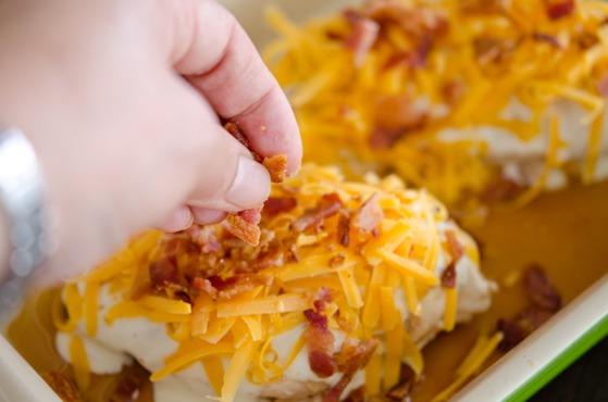 Chicken breasts are topped with shredded cheese and bacon pieces.