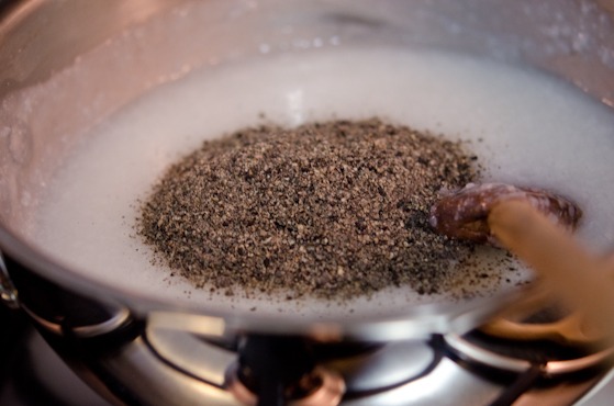 Ground black sesame seeds are added to rice porridge in a pot.
