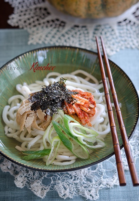 Kimchi Udon with kimchi, bean curd, and seaweed is served in a bowl.