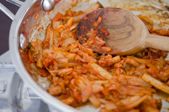 Kimchi is cooked to soften in a skillet.