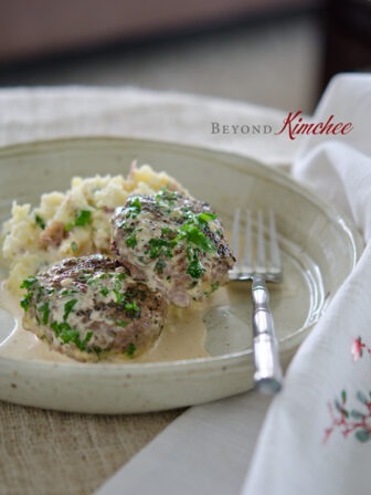 Parsley Peppercorn Beef Pattieswith cream sauce is served with mashed potatoes.