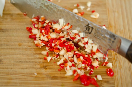 Fresh chili and garlic are minced together with a knife.