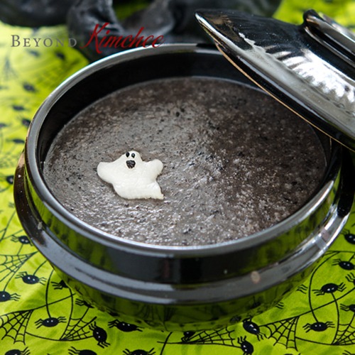 A bowl of black sesame porridge garnished with a baby ghost.