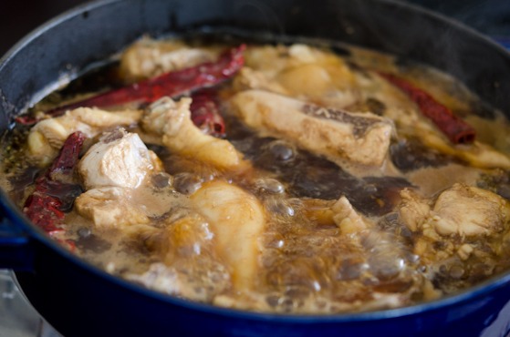 Chicken is braising with chili in cola sauce in a pot.