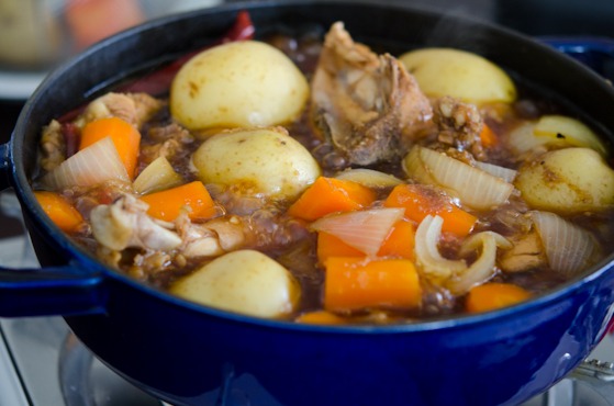 Chicken, potato, and vegetables are braising in a pot 
