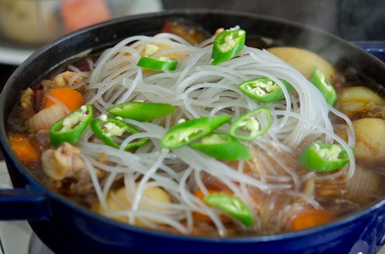 Soaked Korean glass noodles and fresh chili are added to the chicken stew.