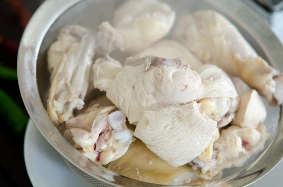 Par-boiled chicken is taken out from the pot.