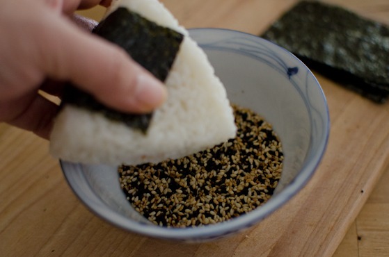 Dip the top of onigiri into toasted sesame seeds.