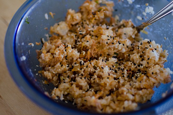 Rice and mixed with kimchi, tuna and sesame seeds in a bowl with a spoon.
