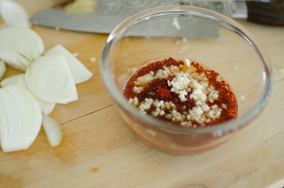 Korean chili flakes is mixed with garlic and ginger in a bowl.