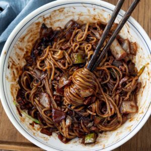 Jjajangmyeon with glossy black bean sauce and pork, noodles lifted with chopsticks