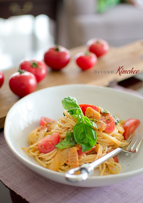 Kimchi Spaghetti with vine ripe tomatoes is garnished with a fresh basil.
