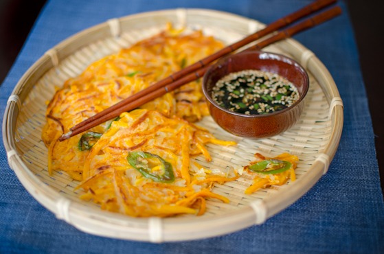 Korean pumpkin pancakes are served with soy dipping sauce in a basket weaved wooden plate.