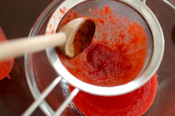 Press down the strawberry puree with a wooden spoon.