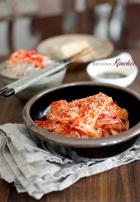 Freshly made kimchi is showing its bright red color and crispy texture in a bowl next to rice.