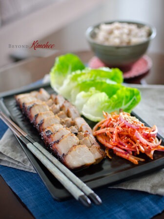 Oven Roasted Korean Pork Belly is served with lettuce and onion salad