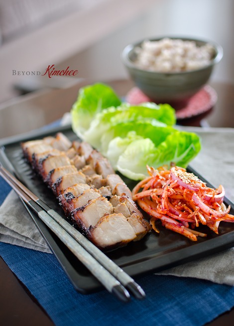 Oven Roasted Korean Pork Belly is served with lettuce and onion salad