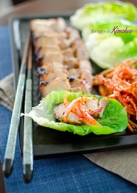 Juicy roasted Korean pork belly is served with spicy onion salad and a pair of chopsticks