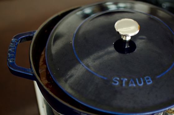 A lid covering a blue pot is slightly opened to let the steam escape.